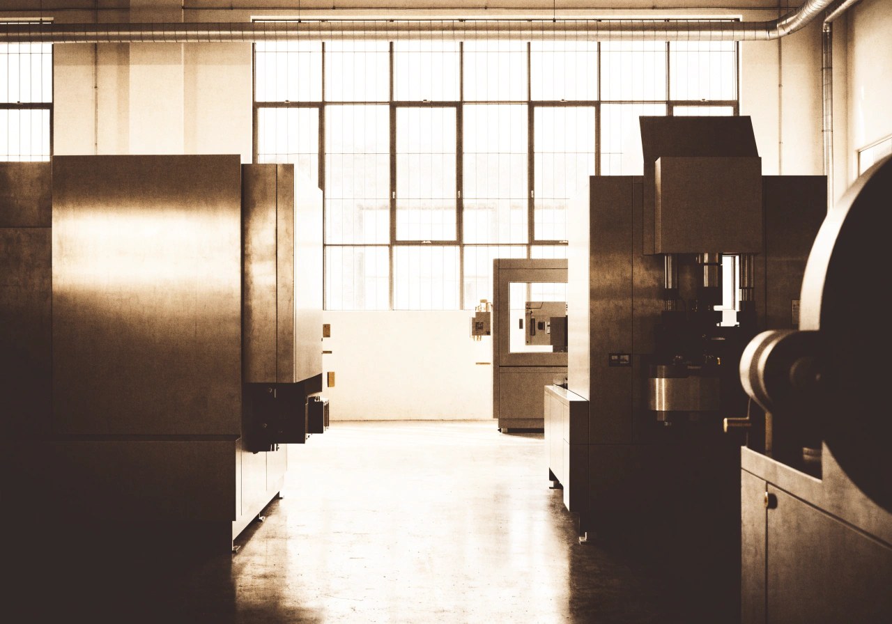Interno di un'officina industriale italiana con luce naturale dalle finestre alte.